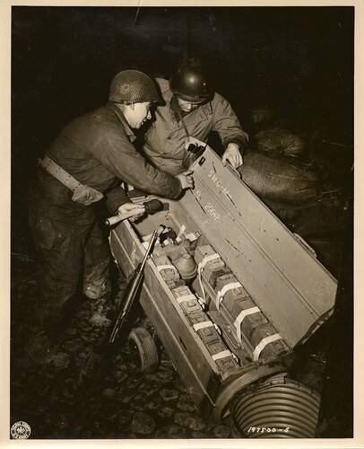 US soldiers examine an airdropped container for the German paratroopers who took part in the attack on US First Army positions in Germany. The wheeled carrier contains hand grenades, ammunition, and bazooka shells. Dec 1944-.jpg